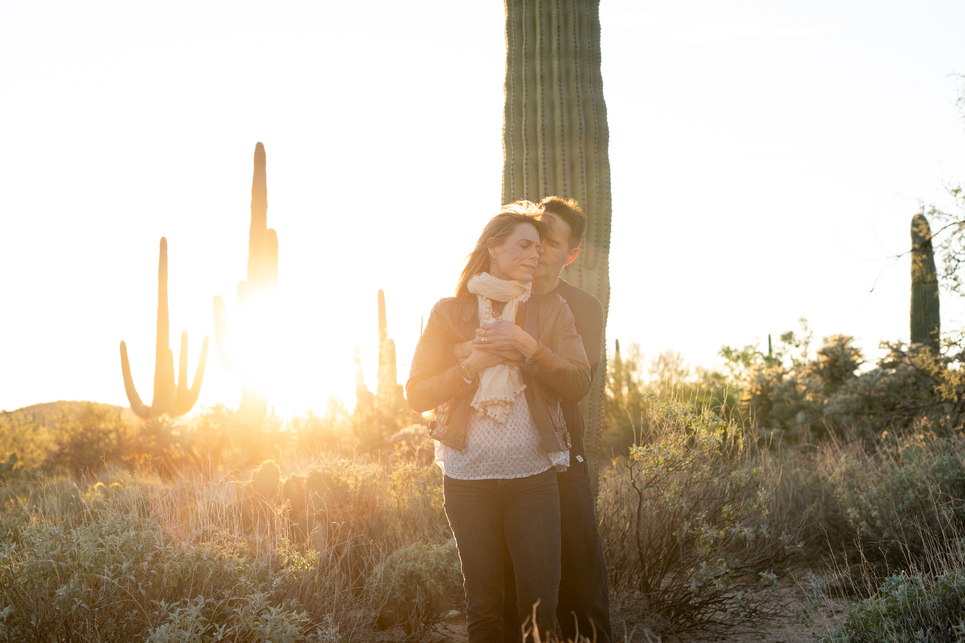 A couple embracing among saguaros at sunset